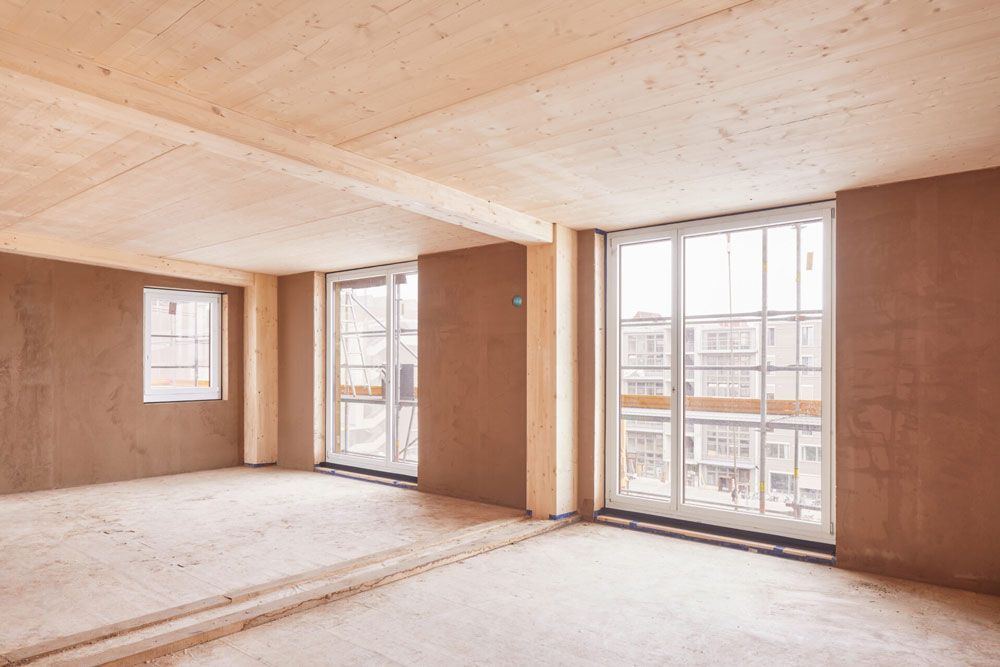 Leerer Raum mit freiliegender Holzdecke und -wänden, große Fenster.