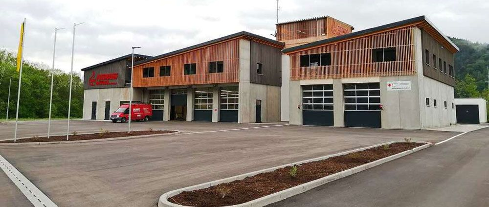 Feuerwache mit drei Garagentoren und Holzelementen; bedeckter Himmel.