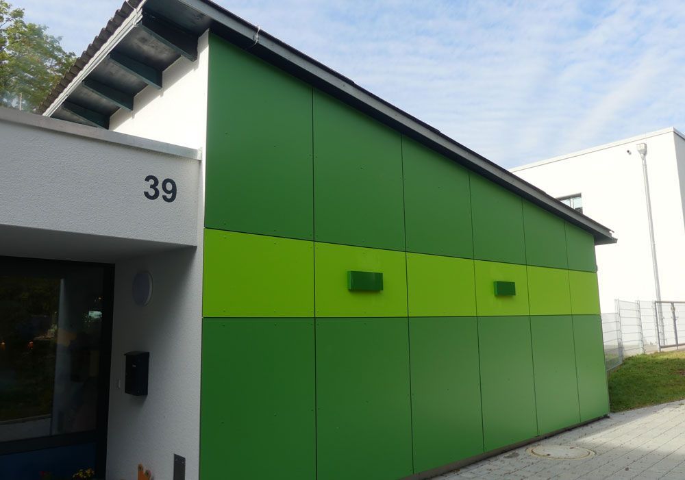 Die Fassade des Gebäudes mit der Hausnummer 39 ist grün und lindgrün getäfelt und steht unter blauem Himmel.