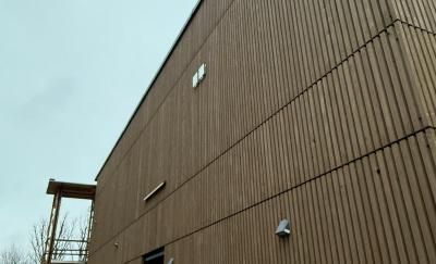 Braune Holzfassade mit vertikaler Holzverkleidung. Himmel im Hintergrund.