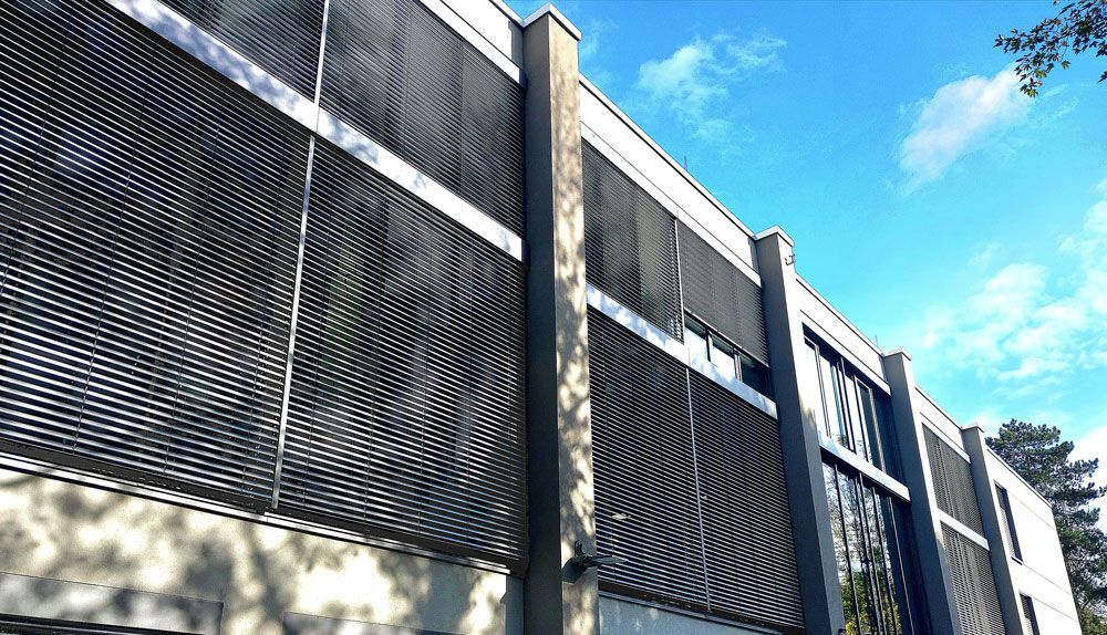 Modernes Gebäudeäußeres mit geschwungener Metallfassade vor blauem Himmel.