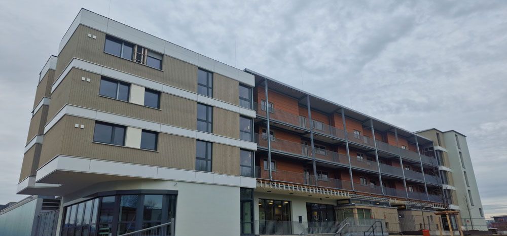 Modernes Apartmentgebäude mit Backsteinfassade und weißen Akzenten unter bewölktem Himmel.