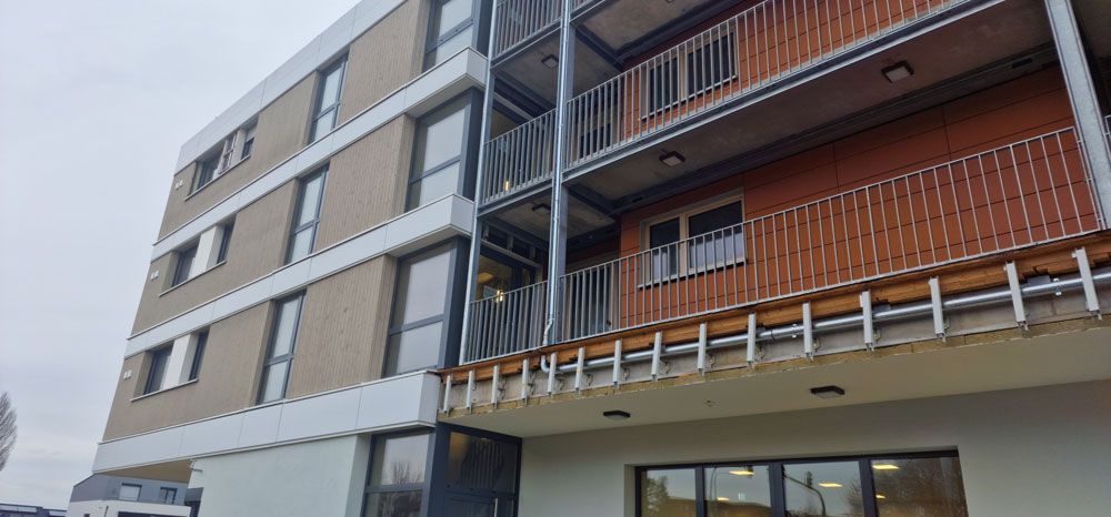 Modernes Mehrfamilienhaus mit Backsteinfassade und Metallbalkonen.