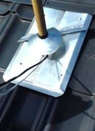 Eine Metallplatte mit einem herausragenden Holzstab auf einem Dach.