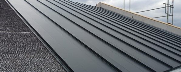 Eine Nahaufnahme eines schwarzen Metalldachs eines im Bau befindlichen Gebäudes.