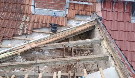 Auf einem Ziegeldach wird eine Holzkonstruktion errichtet.