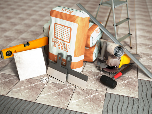 Les accessoires pour poser du carrelage disposés sur un sol partiellement carrelé.