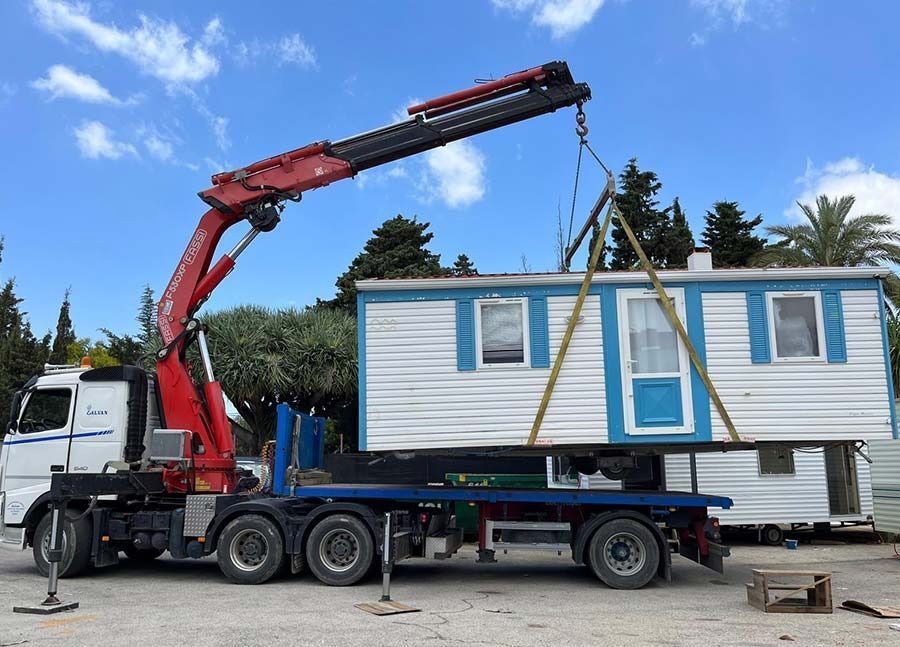 Un camión con una grúa acoplada transporta una casa móvil.