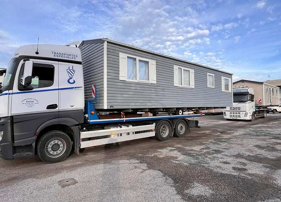 Un camión transporta una casa móvil en un remolque de plataforma.