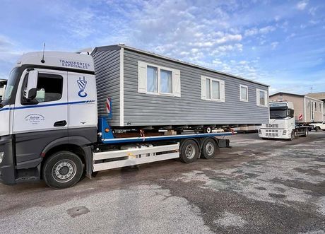 Un camión transporta una casa móvil en un remolque de plataforma.
