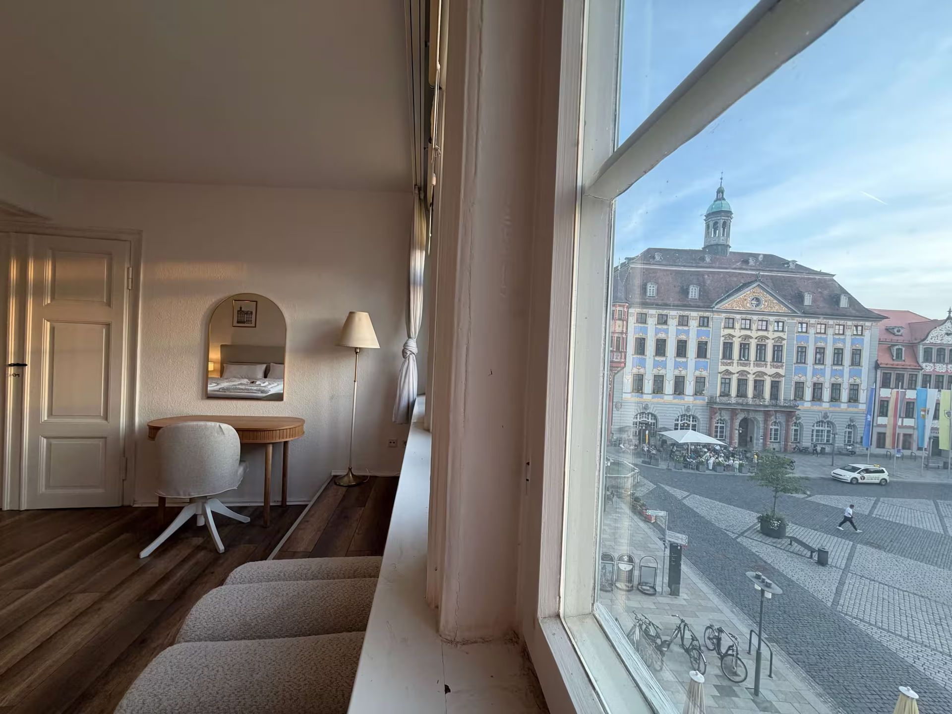 Helles, modernes Wohnzimmer mit weißen Sofas, Fernseher, Couchtisch, Teppich und Stehlampe.