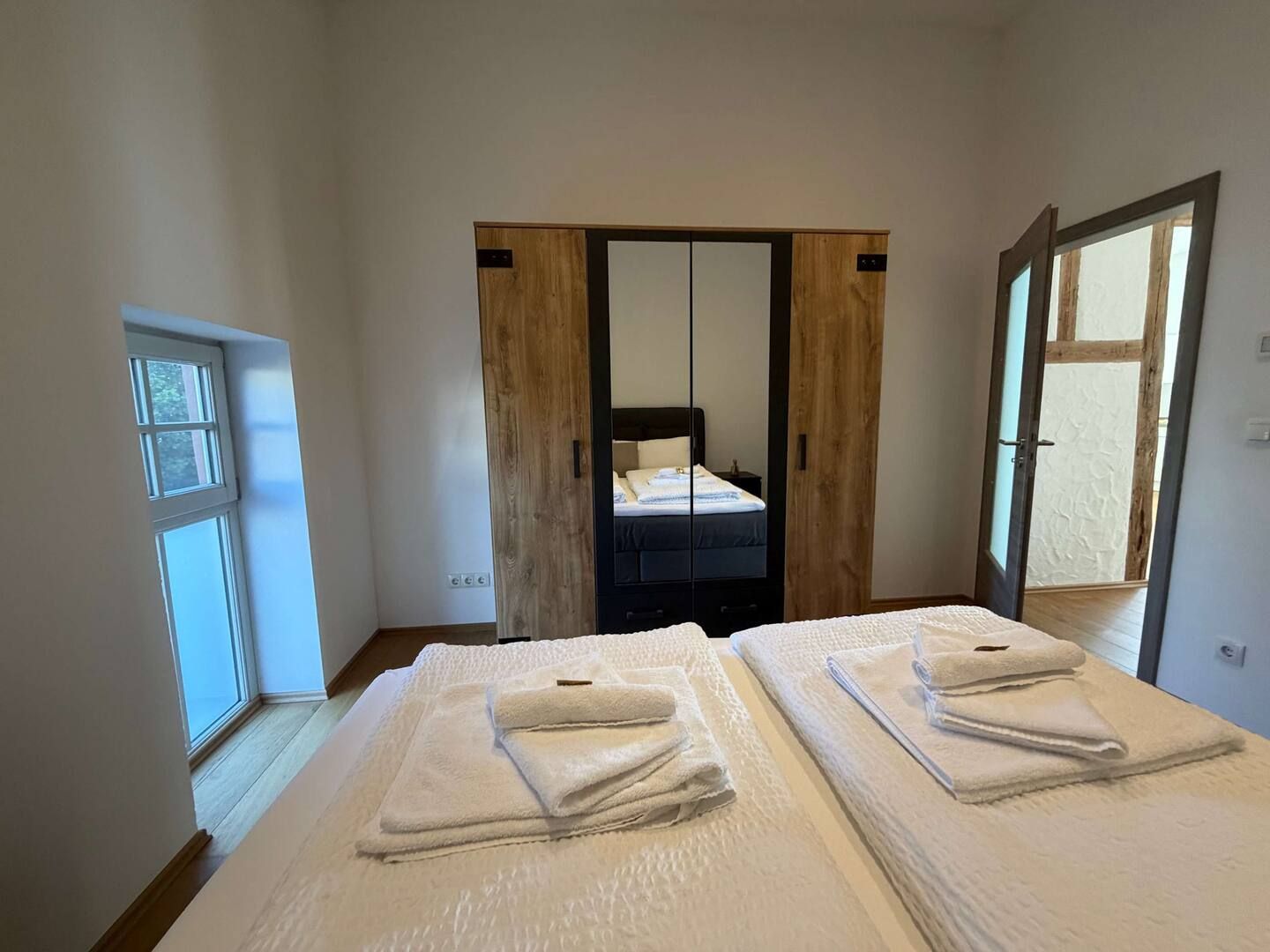 Helle, moderne Wohnküche mit Holztisch, schwarzen Stühlen und großem Fenster.