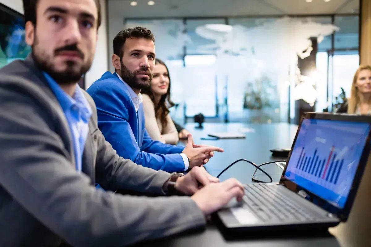 Un grupo de personas está sentado en una mesa con una computadora portátil.