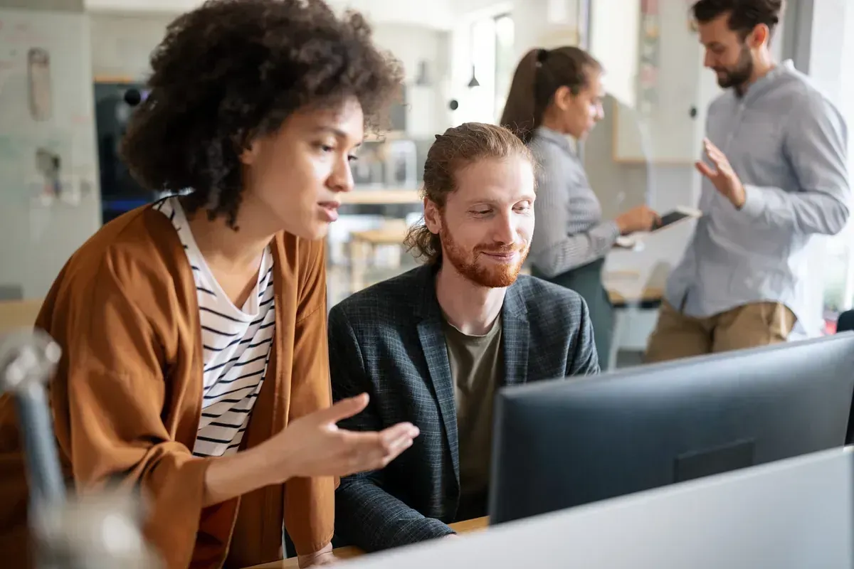 Un grupo de personas está sentada en una mesa mirando una pantalla de computadora.