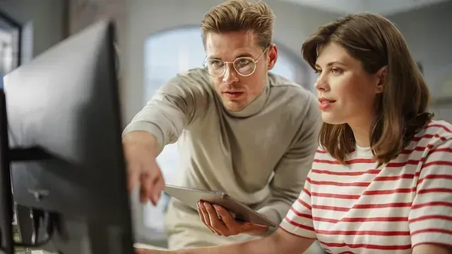 Un hombre y una mujer miran juntos una pantalla de computadora.