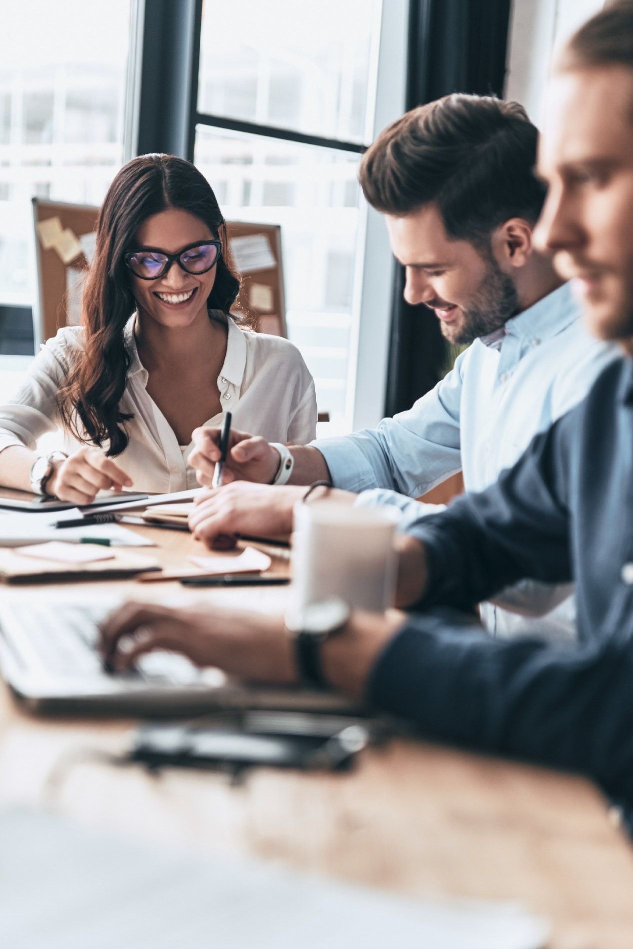 Un grupo de personas está sentado en una mesa con computadoras portátiles.