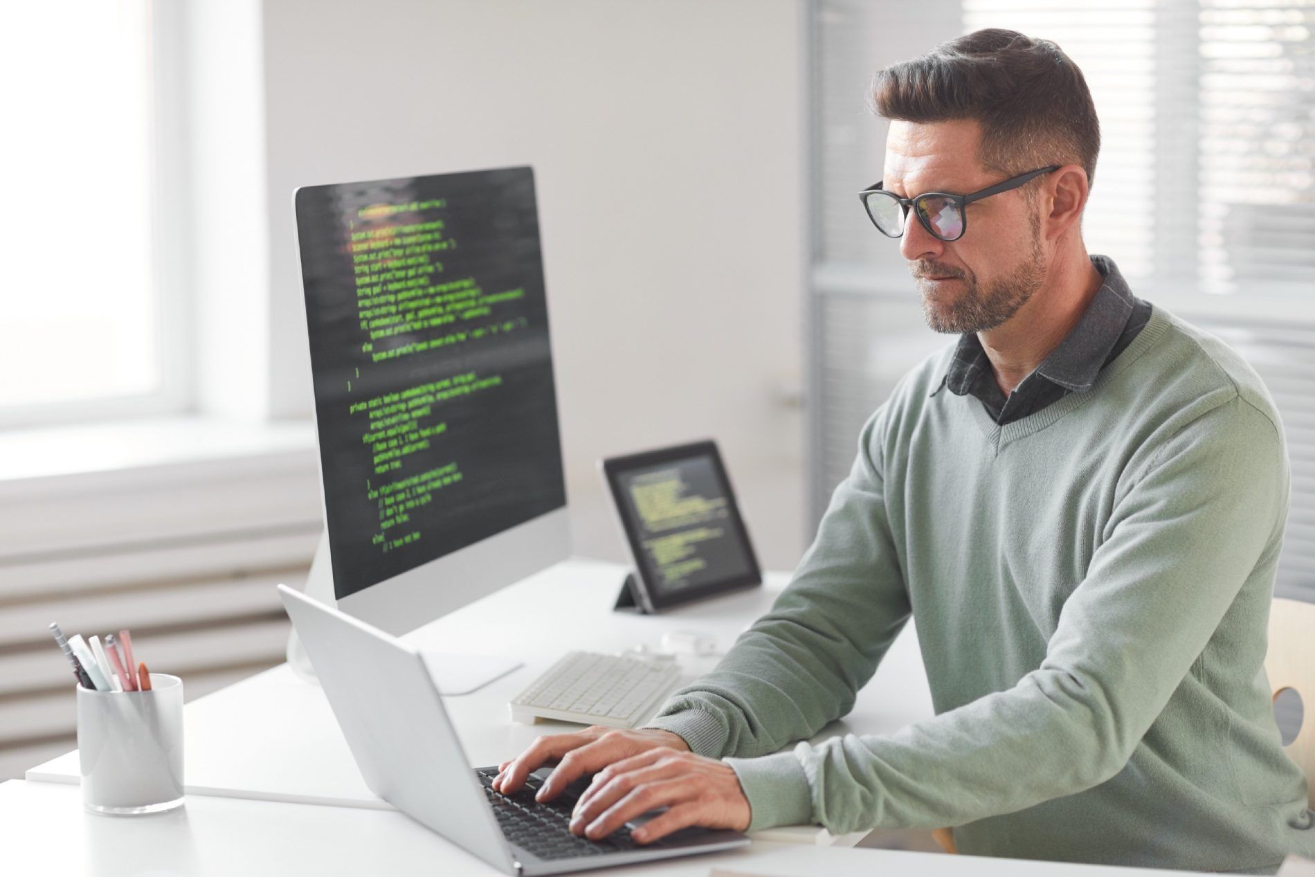 Un hombre está sentado en un escritorio utilizando una computadora portátil.