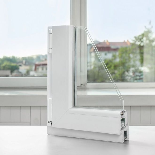 Sección transversal de un marco de ventana blanco con vidrio de triple panel, que muestra la construcción y el diseño, frente a una ventana.