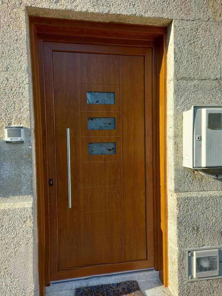Puerta de entrada de madera marrón con inserciones de vidrio rectangulares y manija plateada.