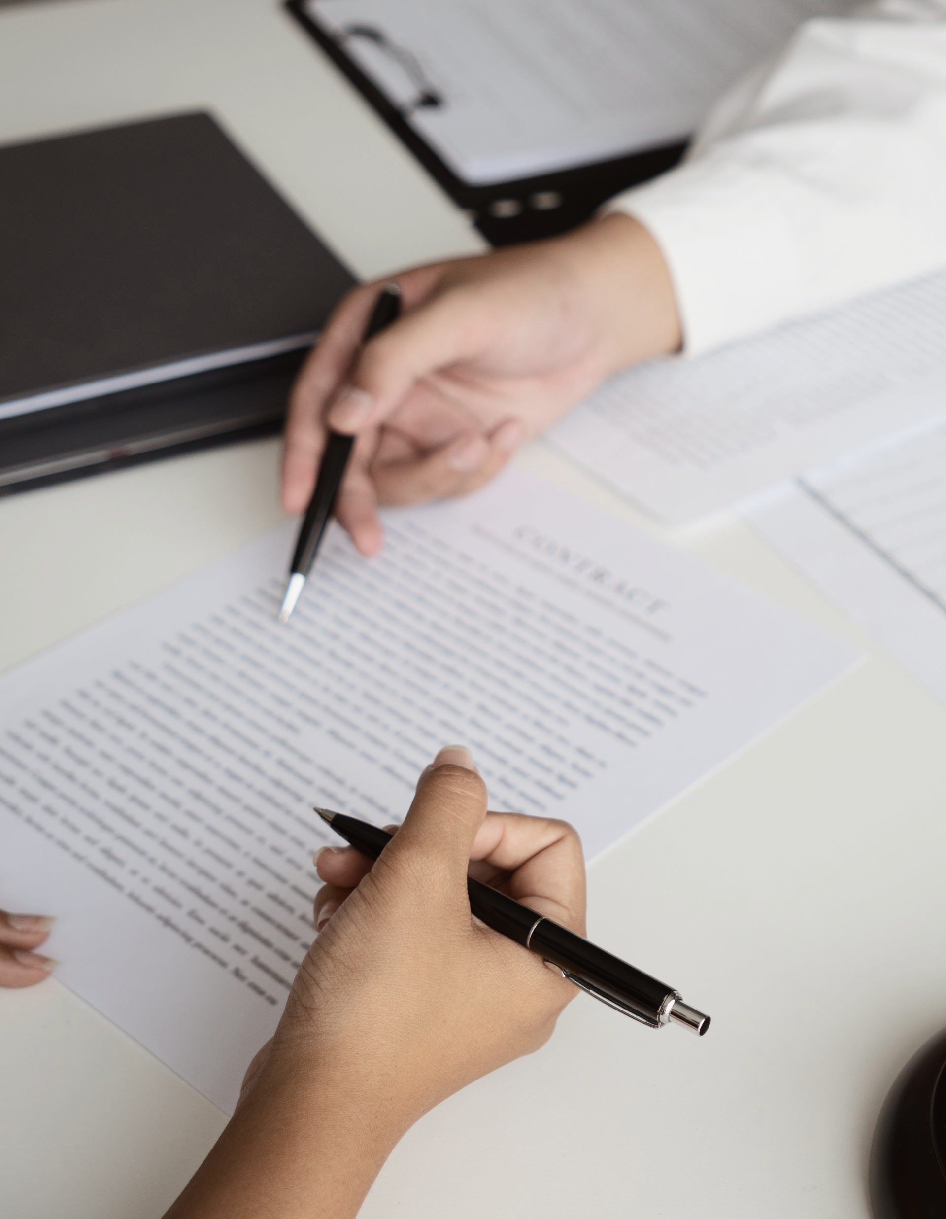 Deux personnes examinent et pointent un contrat avec des stylos à la main.
