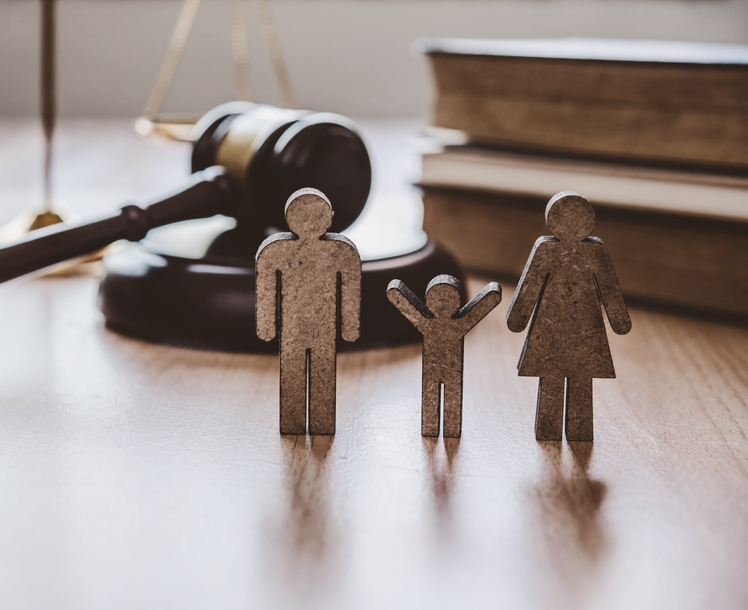 Figurines de famille avec un marteau, des livres et une balance sur une table en bois.