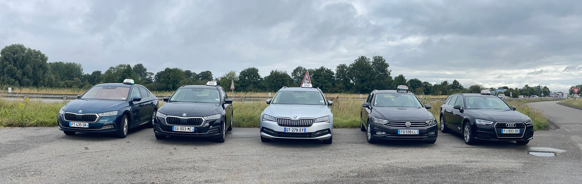 Circulation automobile sur une route, SUV blanc au premier plan, autres véhicules en arrière-plan, journée ensoleillée.