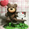 Un oso de peluche está sentado en un banco sosteniendo un globo en forma de corazón.