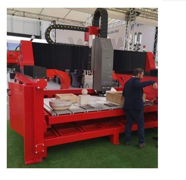 Un homme debout devant une machine sur laquelle est écrit « cnc »