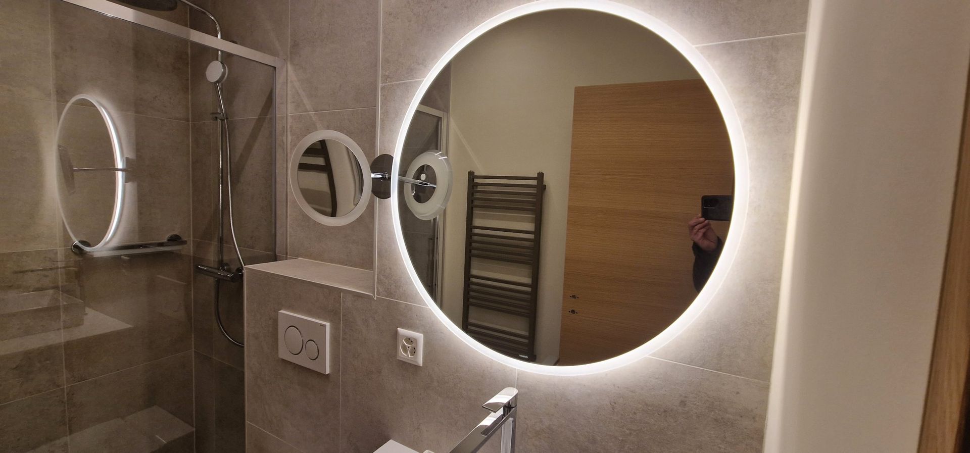 Une salle de bain avec un miroir rond et une cabine de douche.