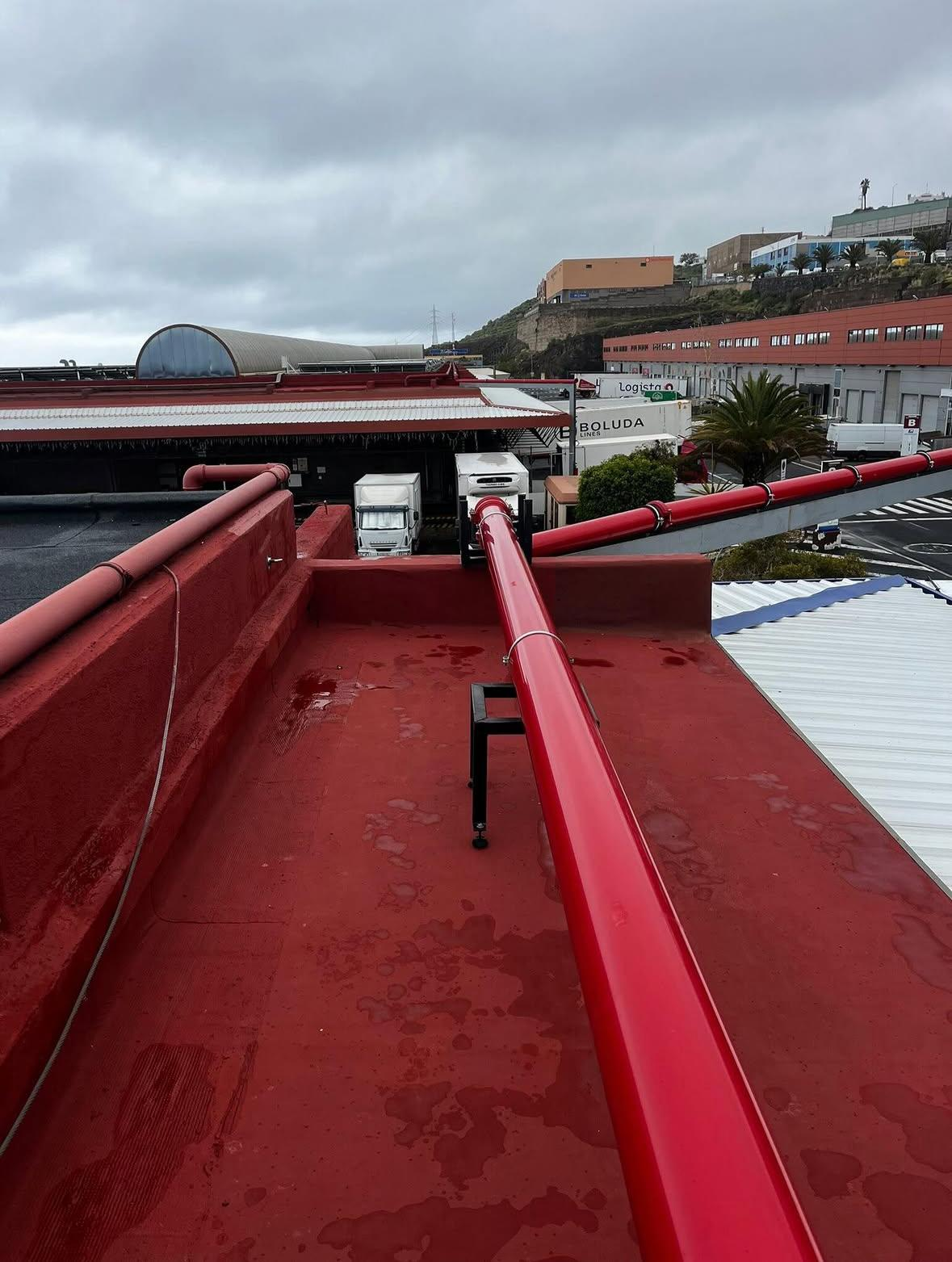 Una manguera contra incendios de color rojo está montada en una pared blanca de un pasillo dañado.
