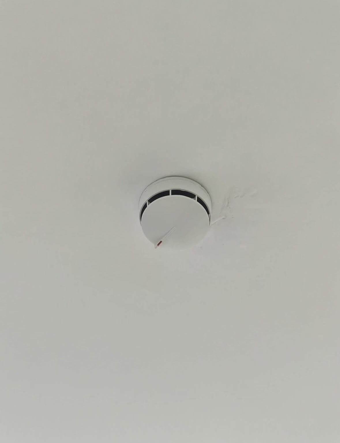 Detector de humo montado en el techo sobre un techo blanco