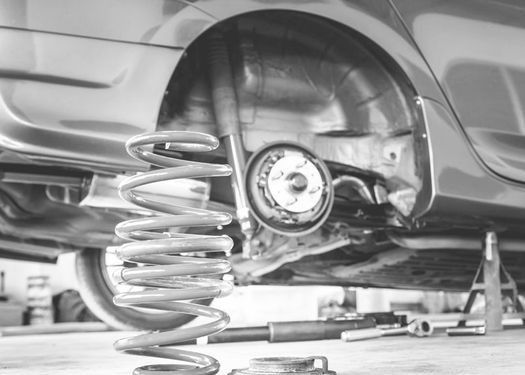 Una fotografía en blanco y negro de un coche que está siendo reparado en un garaje.