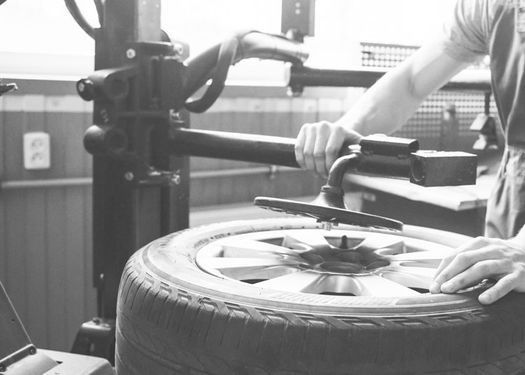 Una persona está cambiando un neumático de una máquina en una fotografía en blanco y negro.