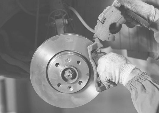 Una fotografía en blanco y negro de una persona limpiando una pastilla de freno de un automóvil.