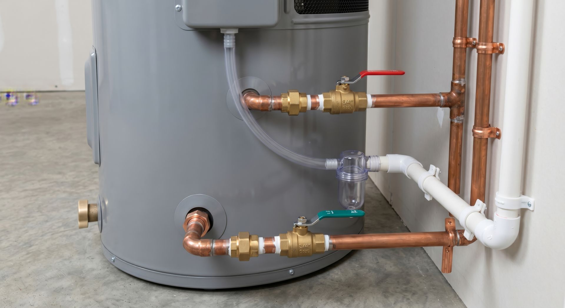Installation de plomberie du chauffe-eau avec des tuyaux en cuivre, des vannes et une conduite blanche isolée contre un mur.