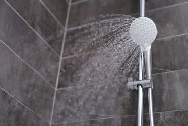 Pommeau de douche moderne projetant de l'eau dans une cabine de douche carrelée.