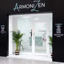 Fachada del spa ArmonZen con exterior negro, entrada de cristal blanco y plantas en macetas.
