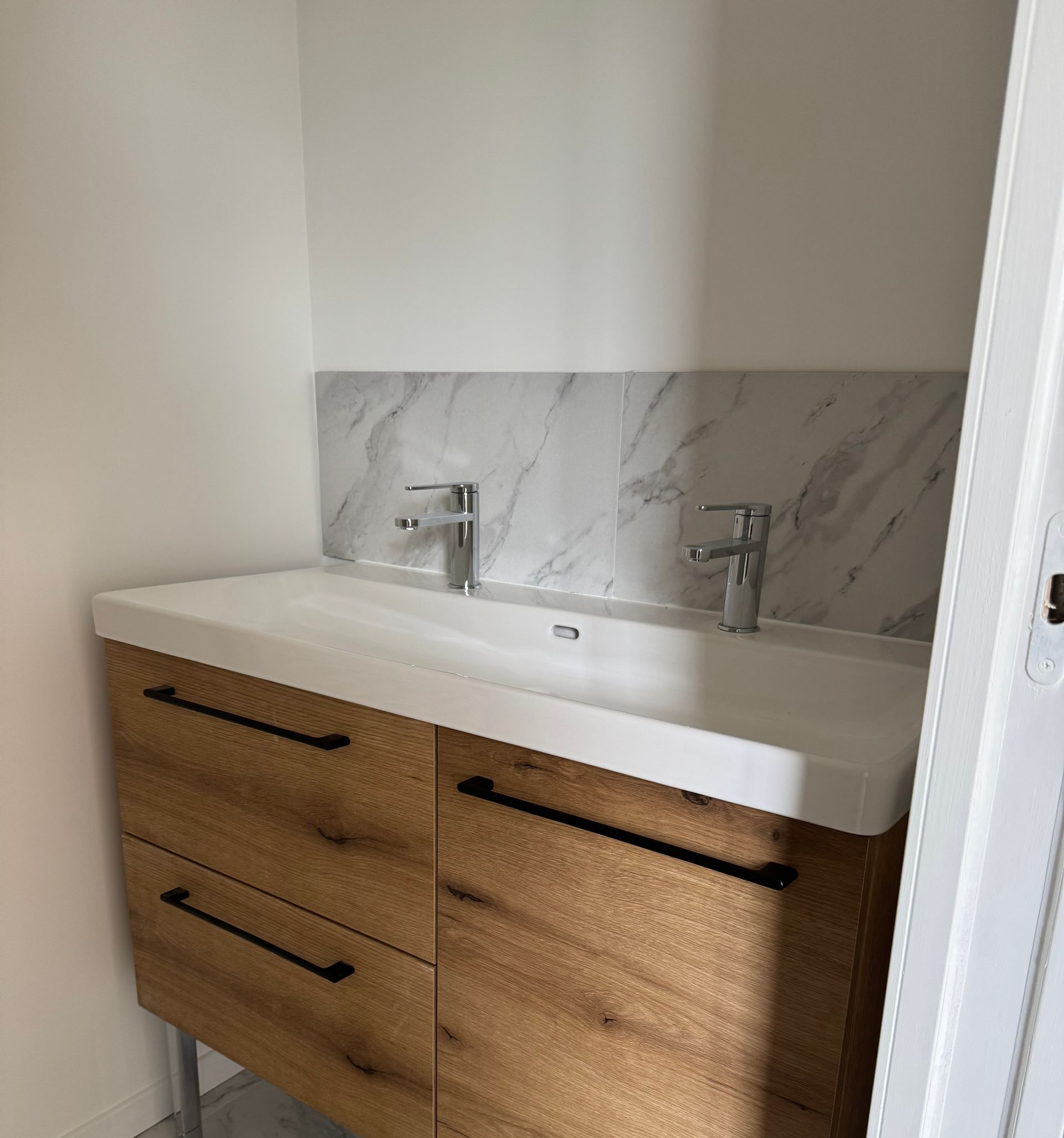 Meuble-lavabo moderne avec double vasque, placards en bois et crédence et sol.