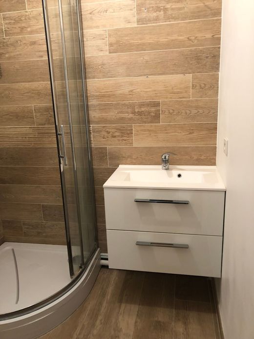 Salle de bains moderne avec douche, carrelage mural et meuble vasque à deux tiroirs.