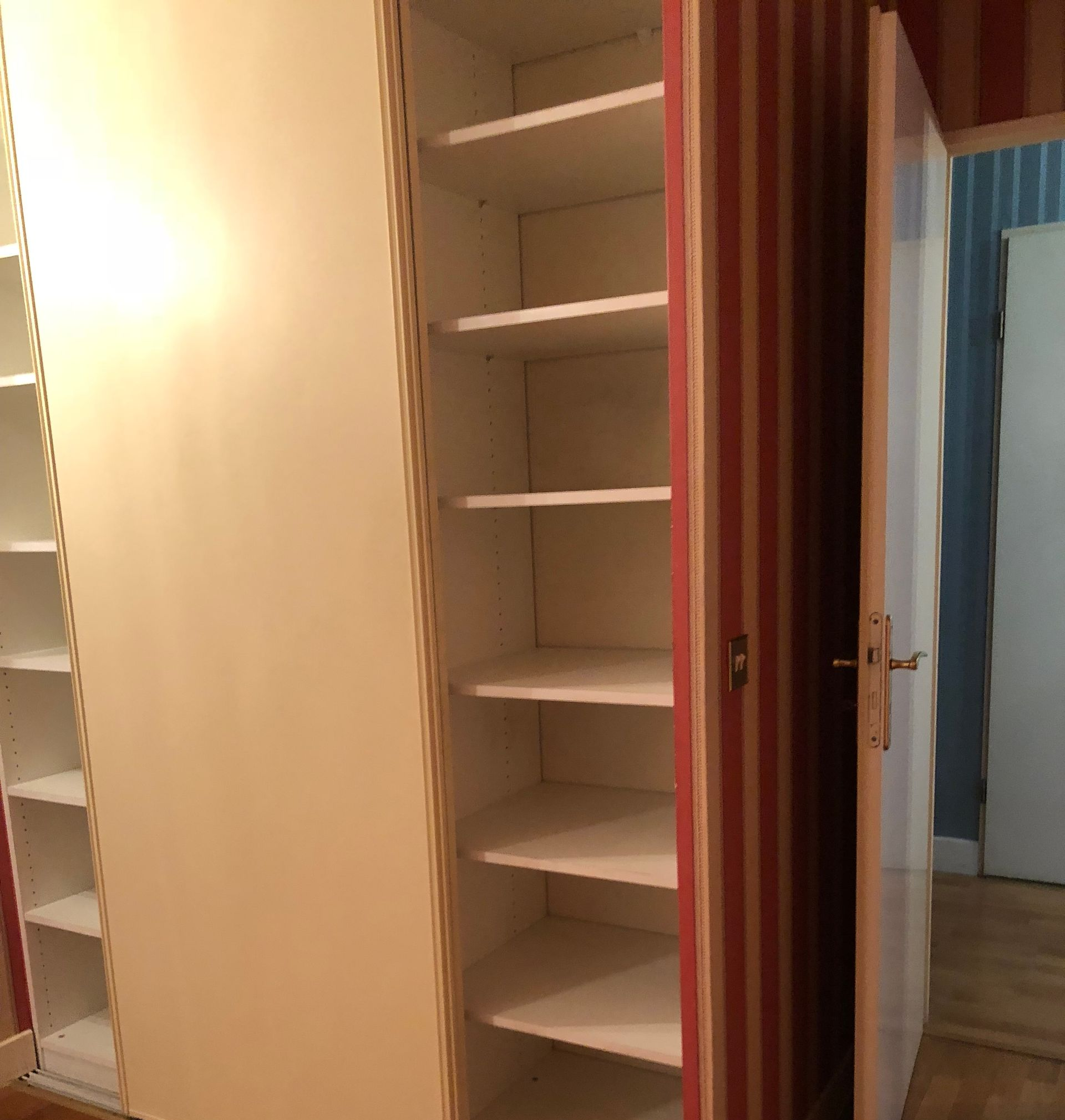 Placard ouvert avec des étagères, une porte coulissante et un rideau, dans une pièce au sol.