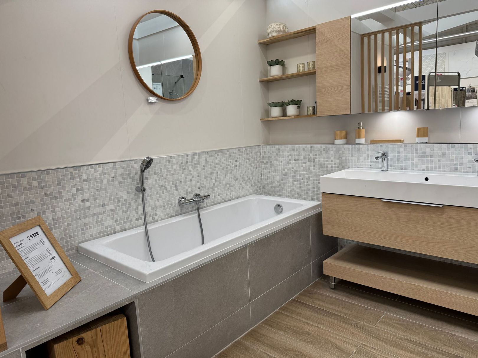 Salle de bains moderne avec baignoire îlot, miroir rond et meuble-lavabo.