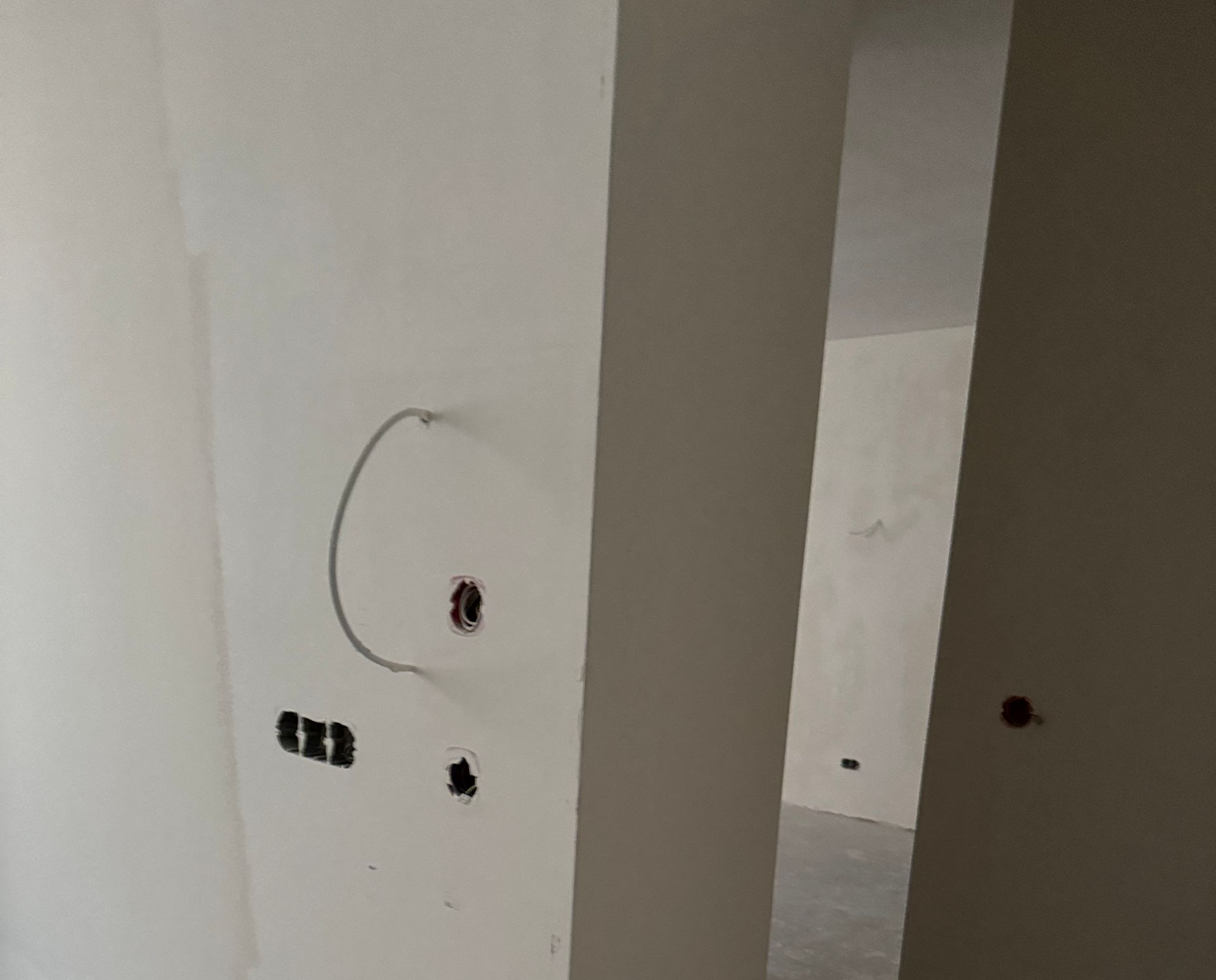 Couloir intérieur, avec des murs, des prises électriques apparentes et un sol en béton.