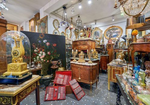 Intérieur d'une pièce rempli d'objets, meubles et cadres de tout style.