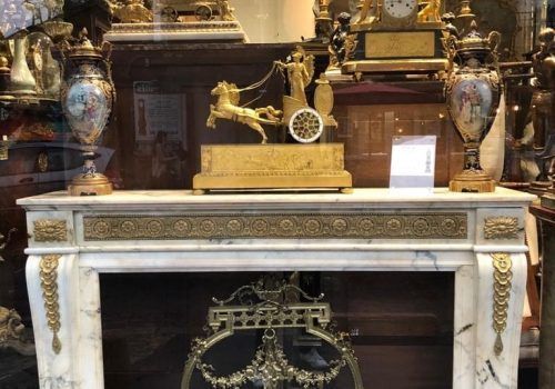 Une horloge et deux vases posées sur une cheminée.