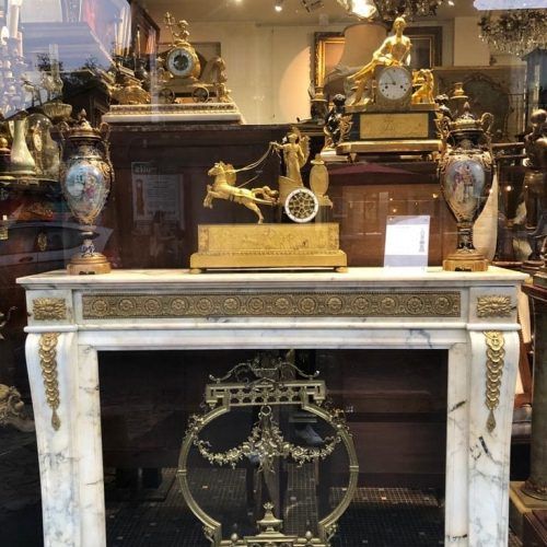 Une horloge et deux vases posées sur une cheminée dans une brocante.
