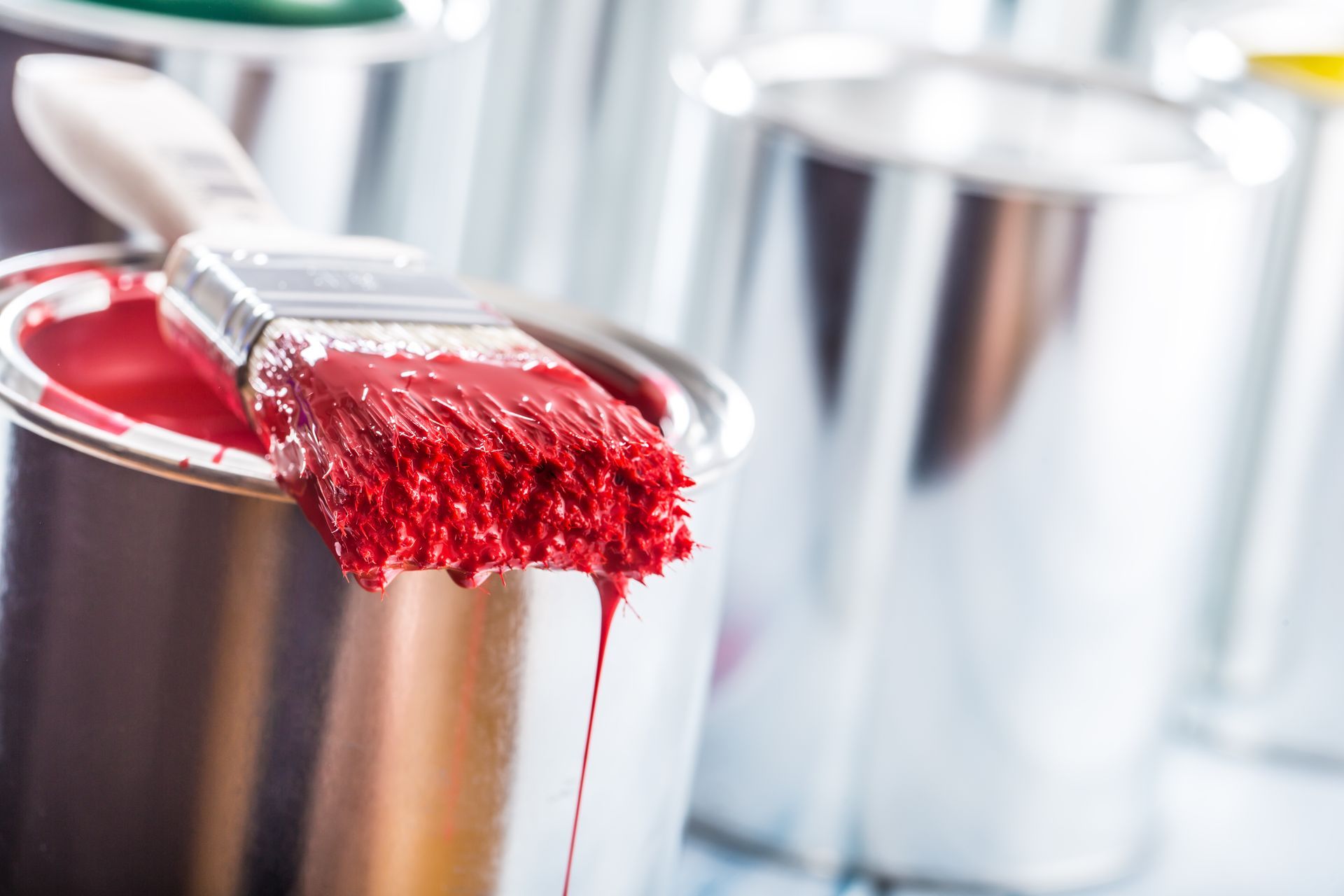 Eine Person in blauer Kleidung streicht eine Wand mit einer Farbrolle hellblau.