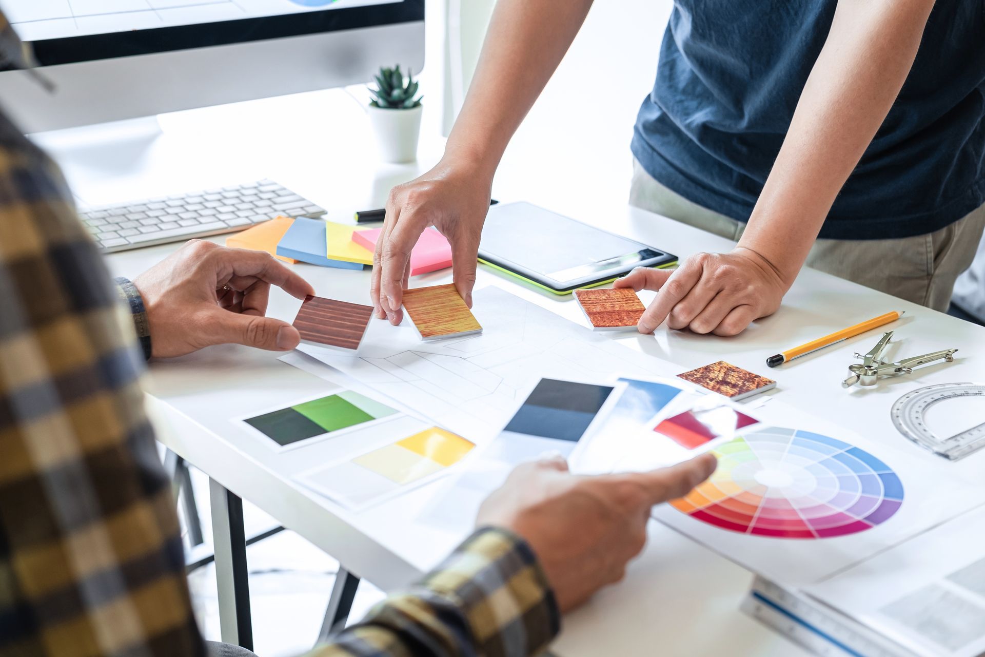 Person, die mit einer Farbrolle eine strukturierte weisse Wand streicht. Roter Griff und rote Rolle.