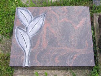 Liegender Grabstein aus poliertem Granit mit stilisierter Blattgravur in heller Farbe.
