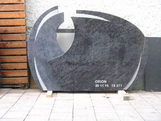 Schwarzer Grabstein mit abstrakter Form und Aussparung beschriftet mit 'ORION 20 11 16 18 311'