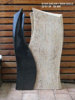 Zwei abstrakte Steinskulpturen, eine schwarz und eine beige, vor einer Holzlattenwand